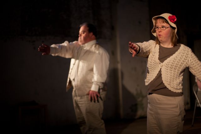 Photo of two dancers in tan costumes dancing with arms extended